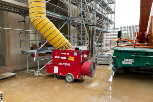 rote Bauheizung führt warme Luft über Warmluftschlauch in Baustelle